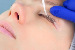 Cosmetologist bending lashes with needle into curlers, lift eyelashes laminaton procedure in beauty salon for woman, closeup face. Beautician making lash lifting in cosmetology clinic, hands closeup.