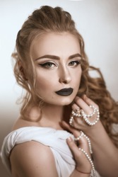 beautiful girl of European appearance in white silk fabric with bright makeup in black