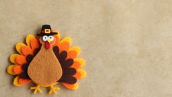 Felt turkey laying flat on a tan background with copy space