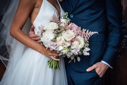 Wedding bouquet of white and pink roses and with newlywed couple
