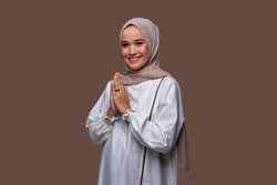 Young woman in hijab posing greeting hand gesture isolated on plain background