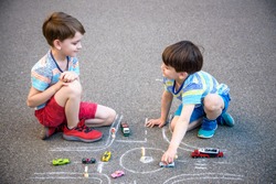 Two brothers sibling kid boy having fun with picture drawing traffic car with chalks. Creative leisure for children outdoors in summer. Difficult traffic rules education friendship concept.