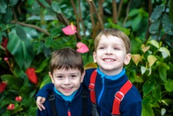 Portrait of two boys, siblings, brothers and best friends smiling. Friends hugging. Happy kids wearing warm closes in orangery park