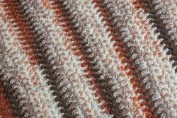 Close up colorful yarn texture background, light beige, dark brown, orange red strains. Shallow depth of focus. Knitting and crochet, craft work concept. Winter clothes. Color combination for styling.