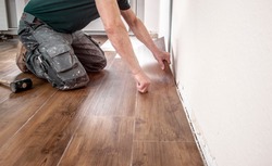 experienced floor layer is laying a new vinyl flooring design