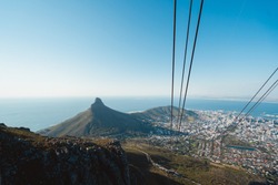 View of Cape Town from the top of Table Mountain as the sun is setting. Views of all of Cape Town with the cable cars and rocky landscape of the seaside town. Bantry Bay, lions head, Camps bay, City. 