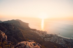 View of Cape Town from the top of Table Mountain as the sun is setting. Views of all of Cape Town with the cable cars and rocky landscape of the seaside town. Bantry Bay, lions head, Camps bay, City. 