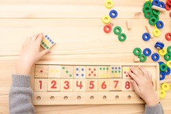 Child math development, learning center, primary school, sorting skills concept. Hands of a Caucasian child playing with a wooden math toy. Number line, counting 1-10. Top view. Desk. Horizontal. 