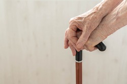 Elderly hands resting on stick. Close up hands of old woman holding walking stick. Hands of woman pensioner on a walking stick closeup. Old lady holding walking stick. Concept of help in old age