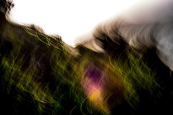Super abstract, motion-blurred, warm green landscape with a touch of multicolor under blown-out sky pattern background texture