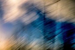 Hazy, fragmented, streaking trees under cloudy blue sky - abstract, motion-blurred background texture