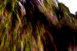 Cascading, warm multicolored, mountainside vegetation light-streak pattern with heavy shadows - abstract, motion-blurred background texture 