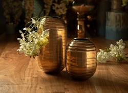 Beautiful gold vases, with artificial flowers, on a wooden table, household items, retro