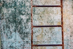 Closeup of rusty corroded metal ladder in abandoned place in front of textured background