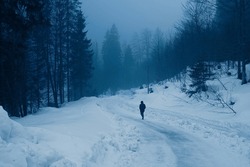 lonely man walking on frozen trail in alps in winter
