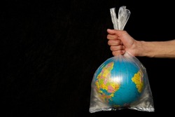 Earth wrapped up in plastic bag. Globe in a plastic bag. Concept of plastic pollution of the earth. World Environment Day concept. Copy space. Save Earth Concept on black background Selective focus