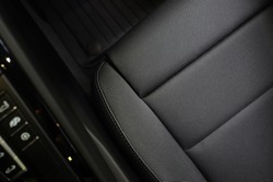 High angle view of luxury sport car front passenger seat and detail high end fabric and stitch texture along with blurred gear shift control buttons. Design element and car interior background.