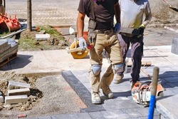 Landscaping company workers working on  residential construction site and laying paving stones for quality interlock home renovation landscape project. 