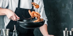 Chef cooking with Tiger prawn on dark background