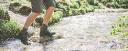Male legs, in waterproof sports hiking boots, walking on water(river)