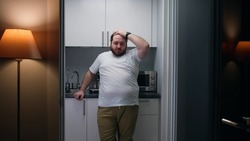 Portrait of frustrated overweight man stand in small kitchen. Stressed and worried fat guy cry at home