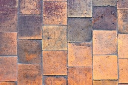 Orange brown purple old shabby worn out floor tiles with damages cracks dirt caverns potholes and paint stains. Art design background texture.