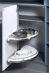 Kitchen access mechanism Magic corner for Blind Corner Cabinets. Solution for a kitchen corner storage in cupboard. Corner unit with rotary mechanism pull out shelves for cookware, ajar.