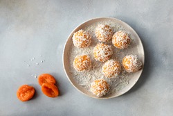 vegan energy balls with dried apricots and coconut in ceramic plate. vegan alternative food. Gray background. top view. copy space