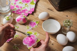 woman apply  glue on colored Easter egg, with the technique of decoupage