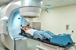 A young woman is undergoing radiation therapy for cancer in a modern cancer hospital. Cancer therapy, advanced medical linear accelerator.