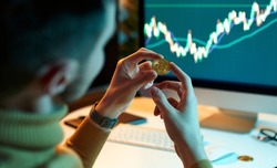 The man checks and controls the financial database on international exchanges holding gold bitcoins. Crypto trader investor analyst looks at laptop screen, analyzes financial chart data