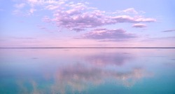 Stunning pink-purple sunrise on the Kiev Sea. Seascape with azure water and purple clouds in reflection. Tourism and recreation.