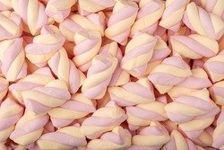 Close up macro photograph of pink and yellow marshmallow twisted candy abstract background
