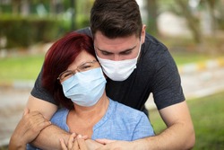 Mom and son hugging and gifts. Medical masks protecting mature woman and son from viruses. mothers day concept.
