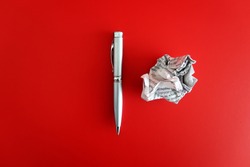 A pen and a crumpled paper on red background with copy space on the left. Concept of first time writting / writers block/ journey to be a good writer.