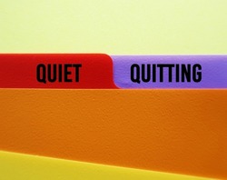 Office folder with text on tag QUIET QUITTING, when employees not engaged or taking job seriously, do minimum required but focus on job outside office