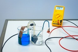 Principle of a rechargeable copper-zinc battery. Blue copper sulphate and transparent zinc sulfate are connected with a salt bridge. The voltmeter indicates just over 1 volt. Used in chemistry class.