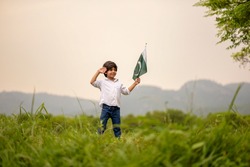 cheerful active little boy celebrating 14th of August, Pakistan Independence day with waving Pakistani flag. F-9 Park Islamabad, Pakistan. 