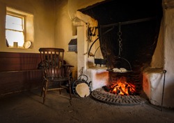 The wooden chair in the old style antique vintage kitchen with tools and fireplace for cooking