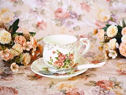 Antique cup of tea with saucer ,yellow orange rose flowers background ,porcelain vintage style ,old English coffee cup still life for wallpaper ,romance roses backgrounds 