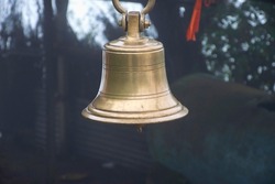 Stock photo of  ancient copper or bronze bell hanging on a iron frame at Hindu temple on blur foggy background. Picture captured at sateri hill station Kolhapur ,Maharashtra, India.