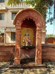 Stock photo of lord Dattatreya temple, beautiful idol of dattatreya with holy cow made from white marble. golden color metal sculpture behind the idol. brown color painted sculptural arch in front .