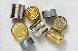 Various tin cans for food preservation on gray concrete background top view. Different canned food in steel cans. Conservation food, donation concept.