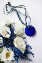 romantic composition. bouquet of blue flowers and jewelry. blue stone pendant isolated on white background 