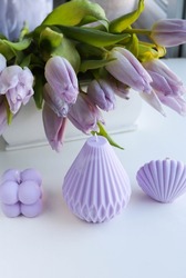 spring composition. a set of natural soy wax candles in lilac color and a bouquet of tulips. color of the year 
