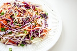 Coleslaw cabbage salad with cabbage, carrots, herbs and sesame seeds on a white plate. Healthy eating, vegan food