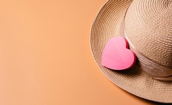 Background for feminine themes with copy space. A background with a travel hat and a heart-shaped notepad paper.
