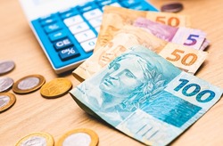 Real - Brazilian money. Brazilian Real banknotes on a wooden surface e with a calculator in the image composition. Concepts of Brazilian economy, investments, finance and debt.
