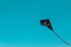 black kite against blue turquoise sky pirate flag kite