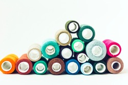 Colored sewing thread coils on white background with copy space for text